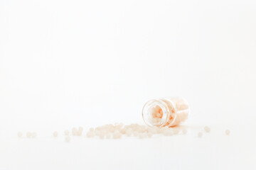 Close-up image of homeopathic globules in glass bottle on white background. Homeopathy pharmacy,...