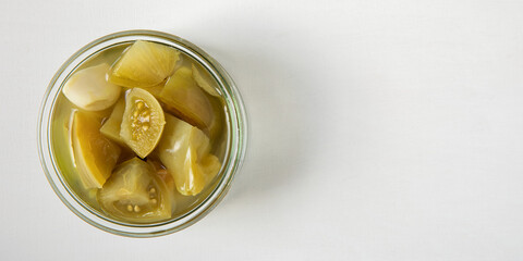 Pickled unripe green tomatoes. Canned homemade home-grown food in jars.