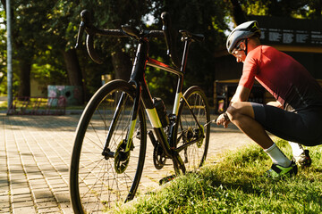 Young white cyclist in helmet inflating tire while working out