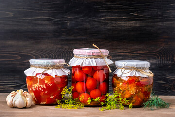 Homemade pickled cherry tomatoes, cucumbers, champignons, garlic, eggplant, red peppers in jars on wooden shelf Homemade canned and fermented foods concept Seasonal product