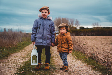 portrait of two children with a lantern in autumn stand on a country road © miguel