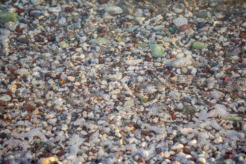 Background of wet stones on a beach surface near water 