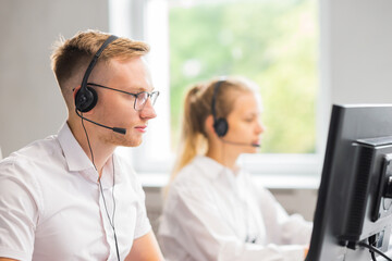 Diverse team of young professionals is working in the phone support office. Working day of sales managers in the call center. Business, telephone consulting and problem solving. - obrazy, fototapety, plakaty