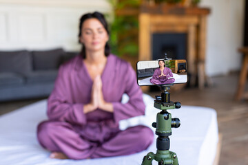 A woman yoga trainer leads an online lesson - the practice of meditation. Online streaming via smartphone.