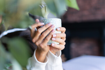 Close up shot of girl's hand holding coffee mug at home with perfect french manicure