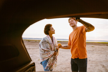 Young multiracial couple smiling and talking while standing by trunk © Drobot Dean