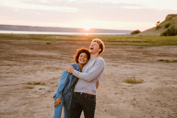 Young multiracial couple hugging and laughing while standing together