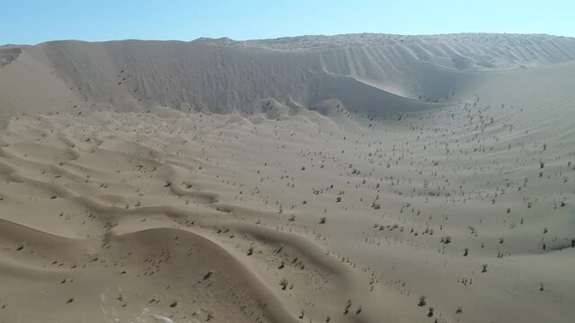 Drone Video Dolly Shot from the formation of great sand dunes and deep valley in dasht e lut desert with blue sky, iran