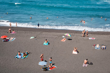 People at beach swimming in ocean in Puerto de la Cruz, Tenerife,