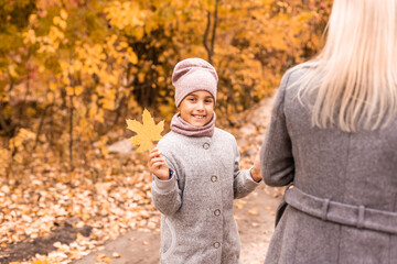 Mother and daughter in autumn yellow park.