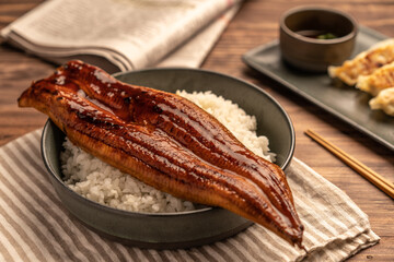Close-up Japanese grilled eel served over rice or Unagi don set on plate. Japanese food on restaurant table