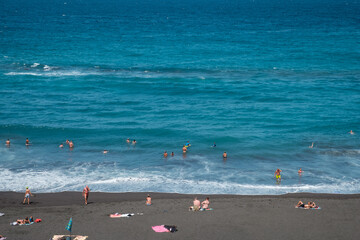 People at beach swimming in ocean in Puerto de la Cruz, Tenerife,