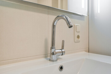 Sink faucet in modern bathroom interior under mirror