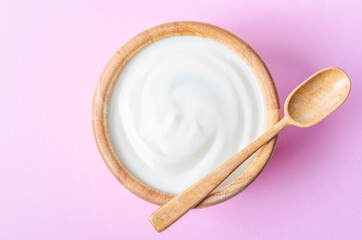 Greek yogurt with wooden spoon in a wooden bowl.
