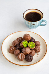 Variety of luxury chocolates on a white background. Along with a cup of coffee