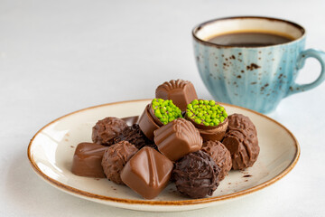 Variety of luxury chocolates on a white background. Along with a cup of coffee