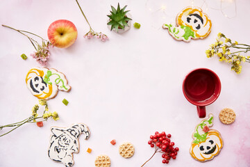 Halloween festive background: red cup, homemade cookies in shape of cute pumpkins and ghost. Atmospheric aesthetic autumn mood or trick or treat concept. Apples, dry flowers, candied fruit. Copy space