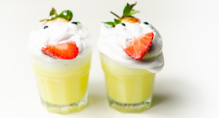 Egg liqueur in shot glass decorated with fluffy whipped cream and pieces of strawberry, served in funny way