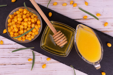 Sea buckthorn juice and honey on a black slate board. Flat lei.