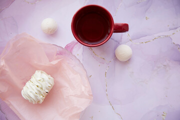 Natural delicate pink and white marshmallow and cup of tea with copy space. Top view. Cozy winter weekends. Homemade sweets. Winter aesthetic.