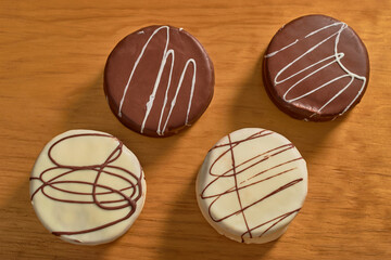 Delicious Argentinean chocolate alfajores on a wooden board. View from above.