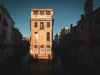 Beautiful and colorful venetian front house surrounded by water during sunset