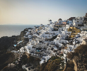 panoramic view of Oia village with traditional white architecture and windmills in Santorini island...