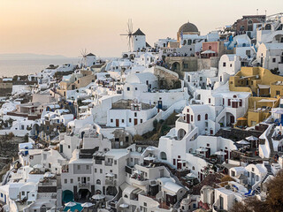 Fototapeta na wymiar panoramic view of Oia village with traditional white architecture and windmills in Santorini island in Aegean sea at sunset, travel background, Santorini, Thera, Greece