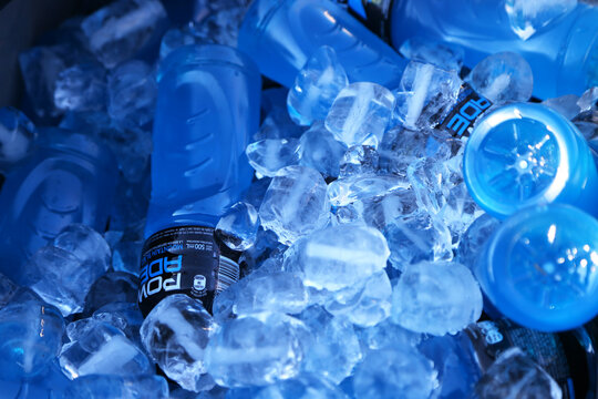 Powerade energy drink. Blue bottle chilling between ice. Drink for athletes. Mountain Blast flavor drink. Blue liquid. Drink for sports or physical activities.