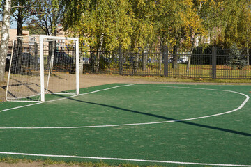 Football green field on the street in the courtyard with a gate with a white net