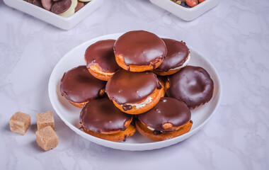 Round custard cakes with cream and chocolate on a white plate