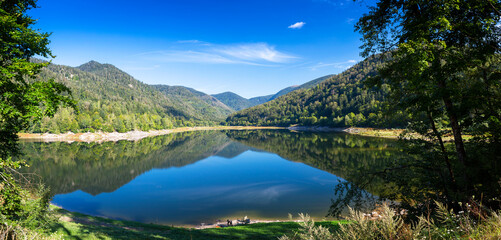 Fototapeta na wymiar Clear lake with reflections and mountains in background in Vosges, France