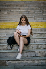 Learning female student preparing for graduation outdoors in summer. 