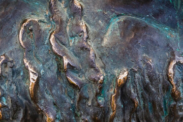 Close-up photo texture of worn and aged copper or bronze statue material with folds.