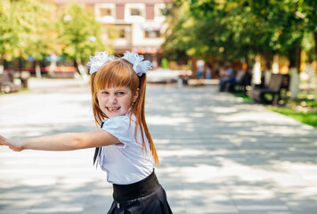 A little girl elementary school student is having fun walking down the street.The child happily...