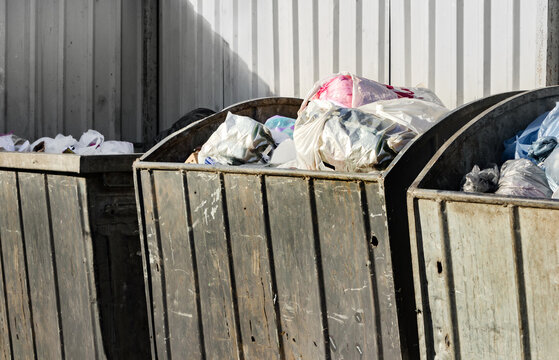Photo of used and worn metal trash bins with garbade.