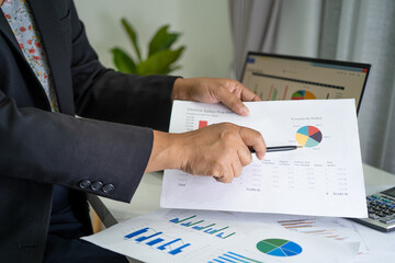 Asian accountant working and analyzing financial reports project accounting with chart graph in modern office, finance and business concept.