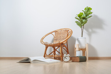 there is a rattan chair, a book, a cup of coffee, and a clock on an empty white wall background