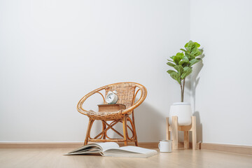 there is a rattan chair, a book, a cup of coffee, and a clock on an empty white wall background
