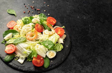 Fresh seafood salad. Grilled shrimp, fresh vegetable salad and egg. Fried shrimps. Healthy food on stone background with copy space for your text