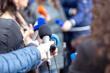 Journalists at news conference or media event, microphone in the focus