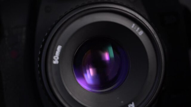 Close-up footage of aperture adjusting in a camera: diaphragm blades of a fixed lens closing and opening. 