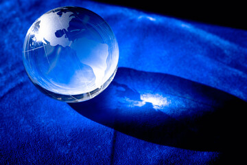 Glass globe on a blue surface. Glass Planet Earth. The concept of the fragility of our planet