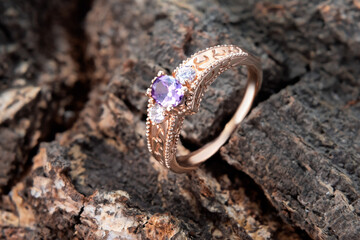 Gold ring with precious stones on stands on a wooden bark