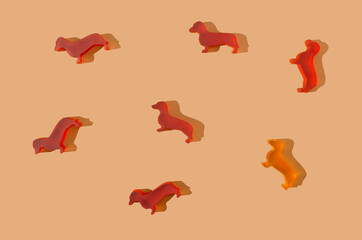 A pattern or wallpaper made of six red dachshunds and one yellow. Light brown background. Creative...