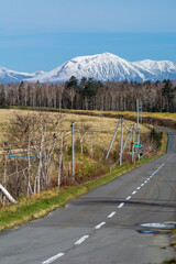 秋の高原の道路と冠雪の山並み　十勝岳連峰
