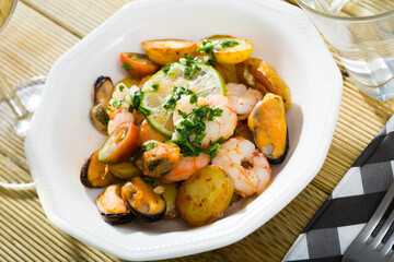 Tasty stewed potato served on plate with seafood - shrimps and mussels