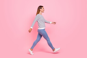 Fototapeta na wymiar Full length profile photo of young nice brown hairdo lady go wear shirt jeans sneakers isolated on pink background