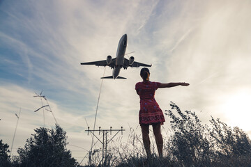 Fototapeta na wymiar a girl in a summer dress and a plane in the sky