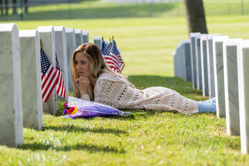 A Grieving Woman Shares Her Emotions With Her Fallen Veteran Family Member At A MIlitary Cemetery